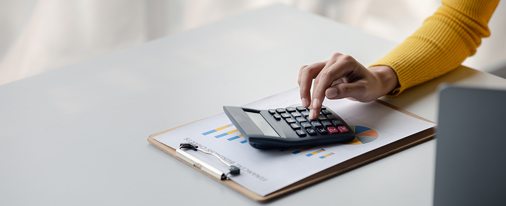 woman using a calculator to calculate numbers on a company's financial documents