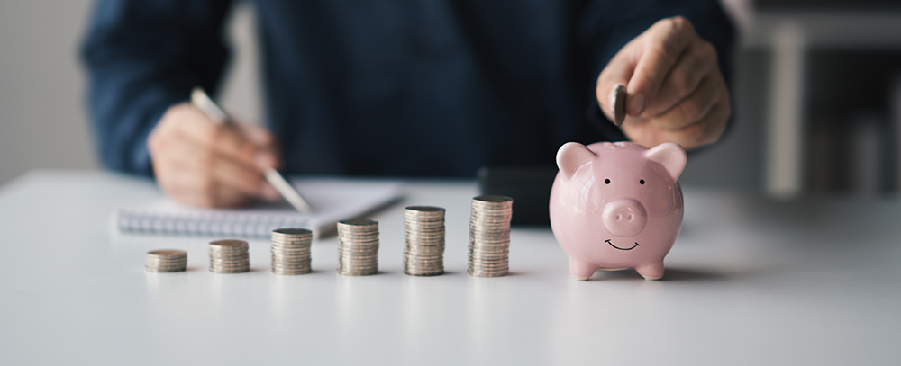 Businessman putting coins into piggy bank